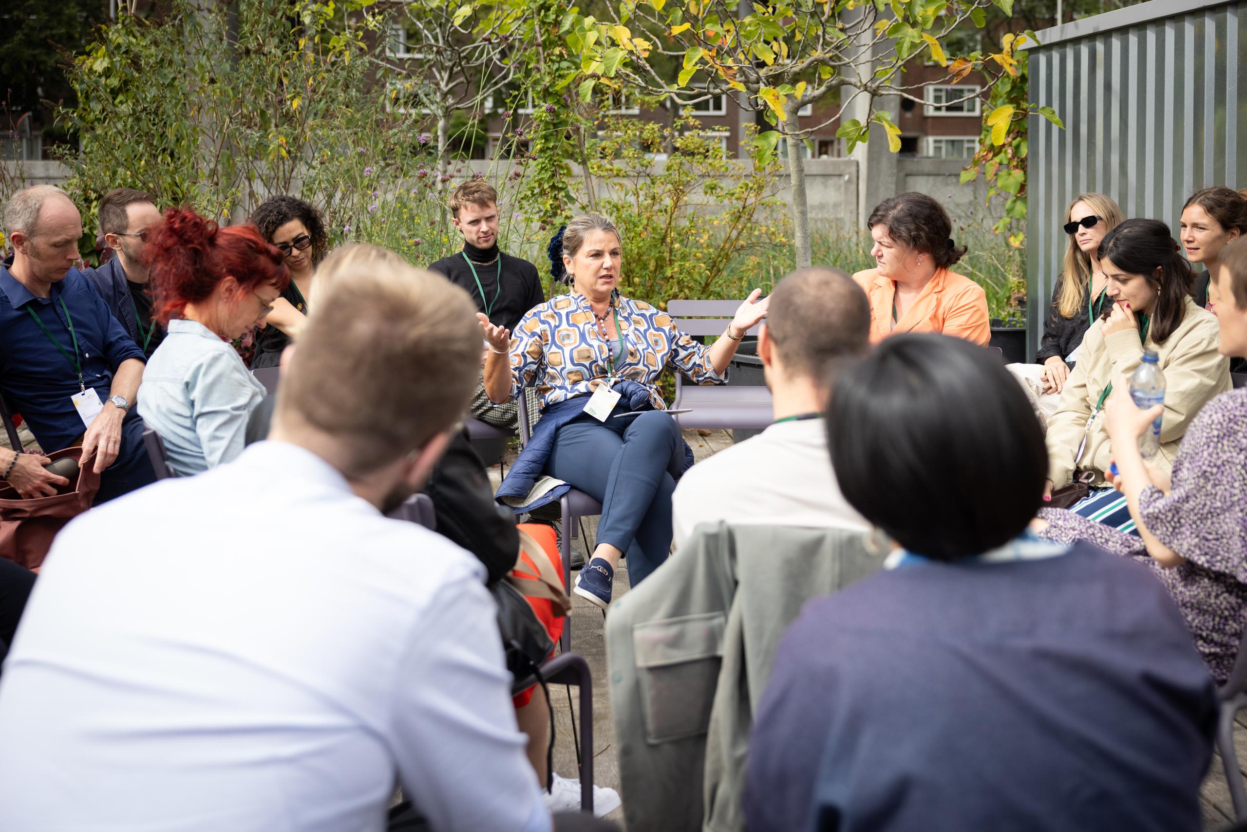 NELA intro image A group of people listening to one person